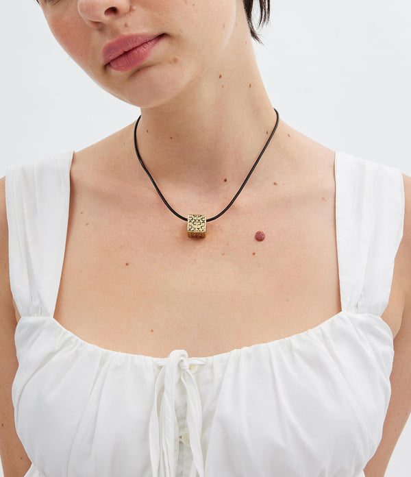 قلادة من الجلد بدلاية على شكل مكعب مبطن مزينة بشعار كوتش